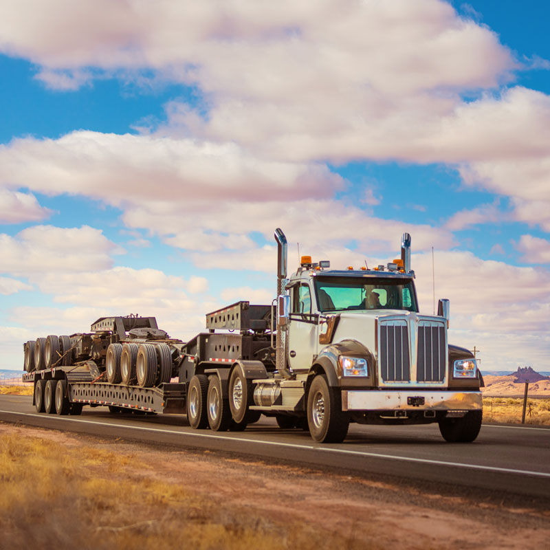 large truck hauling heavy construction equipment on highway