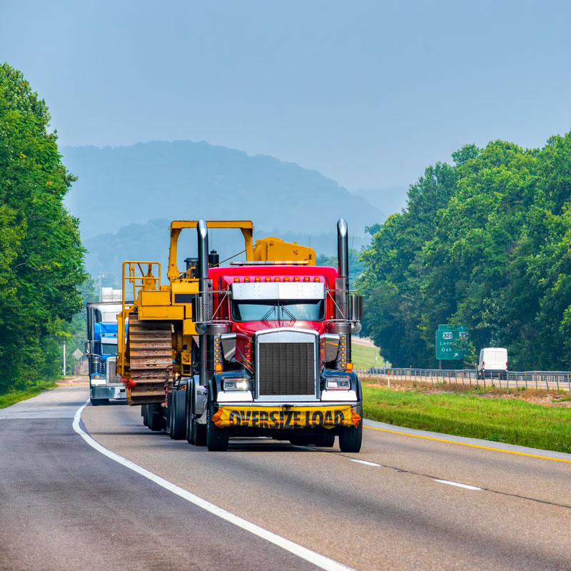 large truck hauling heavy construction equipment on highway