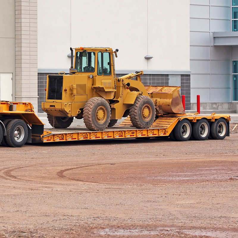 large truck hauling heavy construction equipment