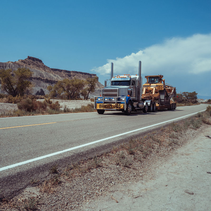 large truck hauling heavy construction equipment on highway