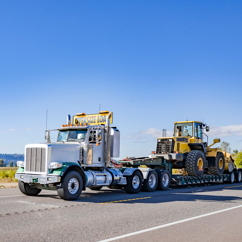 large truck hauling heavy construction equipment on highway