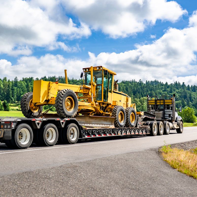 large truck hauling heavy construction equipment on highway