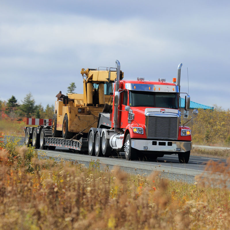 large truck hauling heavy construction equipment on highway
